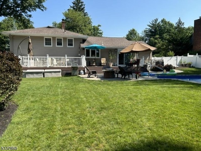 back of property featuring a deck, a patio, an outdoor fire pit, fence, and a yard