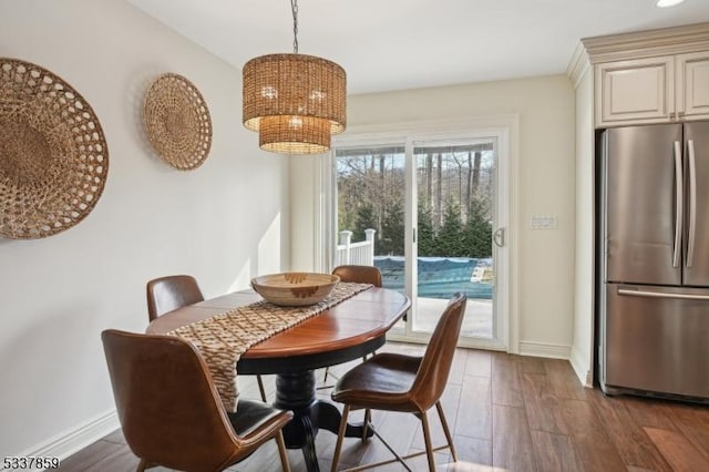 dining space with dark wood-style floors, a chandelier, and baseboards