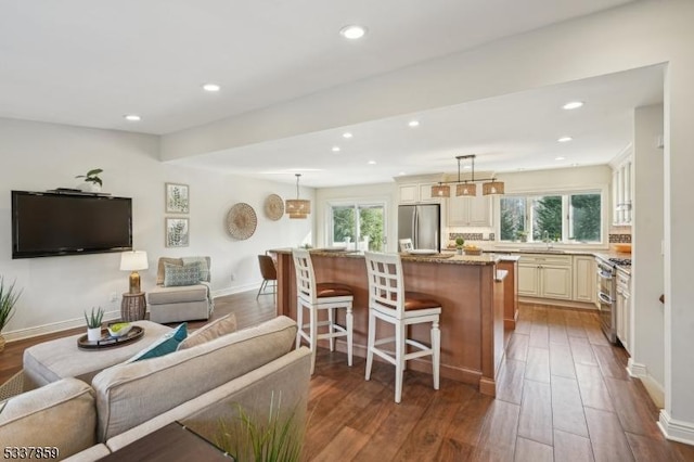 living room with dark wood-type flooring, plenty of natural light, and recessed lighting