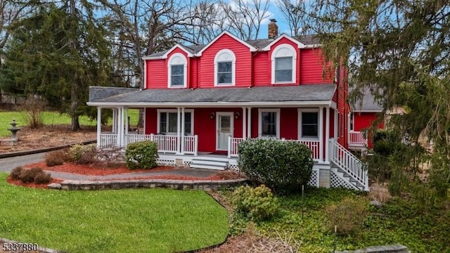 farmhouse featuring a porch, a chimney, a front yard, and a shingled roof