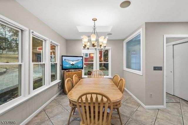 dining room featuring light tile patterned floors, baseboards, a skylight, and an inviting chandelier