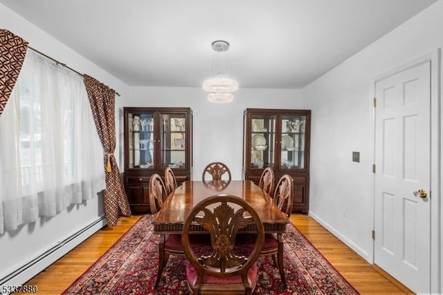 dining room featuring a chandelier, light wood finished floors, and baseboard heating