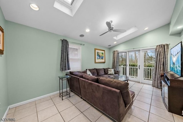 living area featuring lofted ceiling with skylight, ceiling fan, light tile patterned floors, and baseboards