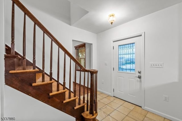 entryway with stairway, light tile patterned floors, and baseboards