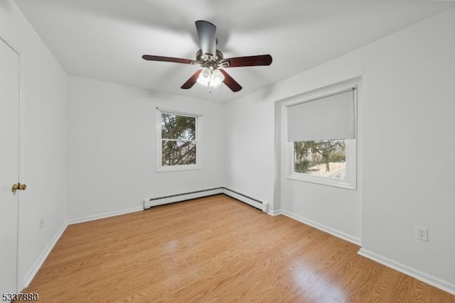 empty room featuring plenty of natural light, a baseboard heating unit, light wood-type flooring, and baseboards