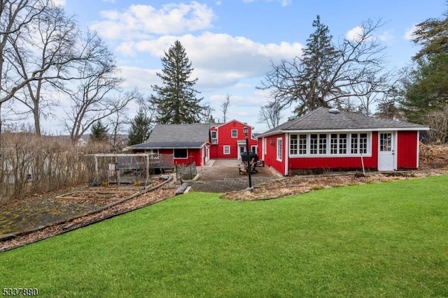 back of house featuring a lawn and an outdoor structure