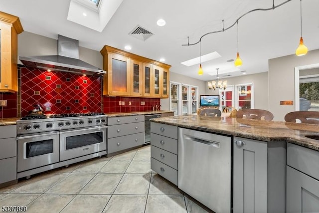 kitchen with stainless steel appliances, gray cabinetry, visible vents, and wall chimney exhaust hood