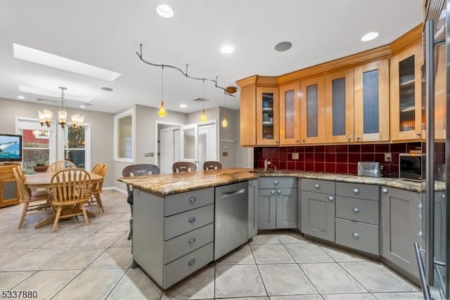 kitchen featuring a peninsula, a skylight, appliances with stainless steel finishes, and gray cabinets