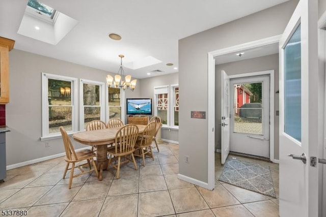 dining room with a skylight, a notable chandelier, baseboards, and light tile patterned floors