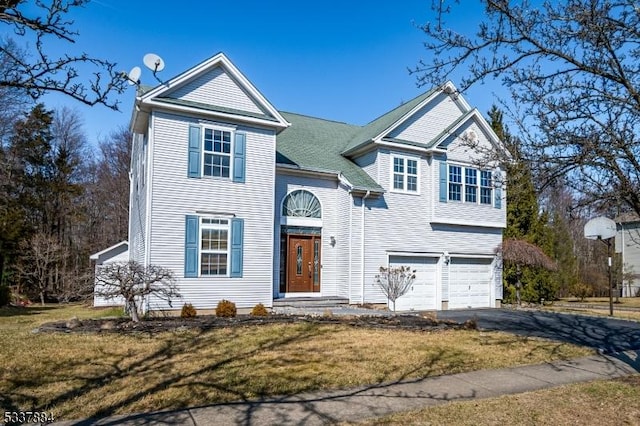 view of front of home featuring driveway, an attached garage, and a front yard