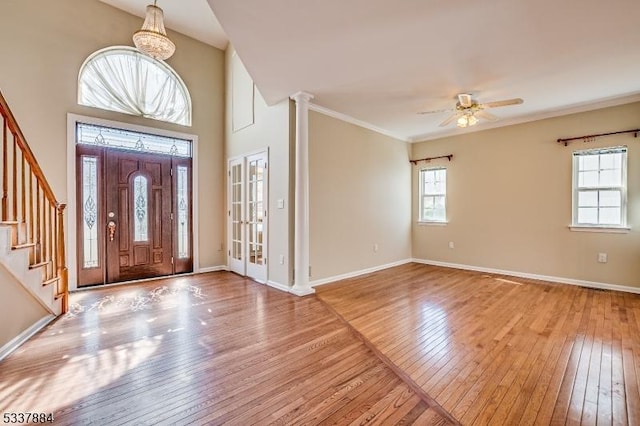 entrance foyer with stairway, wood-type flooring, crown molding, baseboards, and ceiling fan