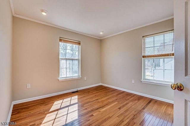 spare room featuring visible vents, baseboards, crown molding, and light wood finished floors