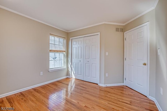 unfurnished bedroom with visible vents, light wood-style flooring, baseboards, and ornamental molding