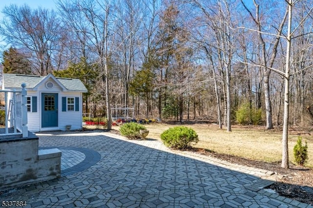 view of yard featuring an outdoor structure, decorative driveway, and a patio