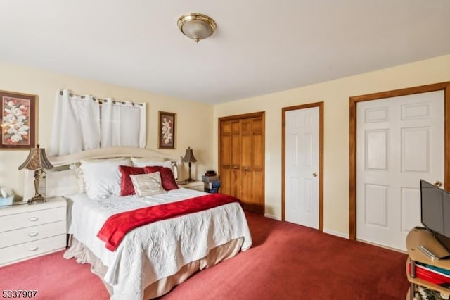 bedroom with carpet flooring, baseboards, and two closets