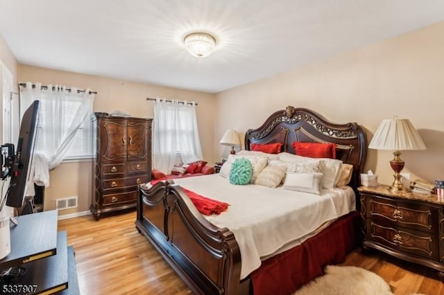 bedroom with wood finished floors, visible vents, and baseboards