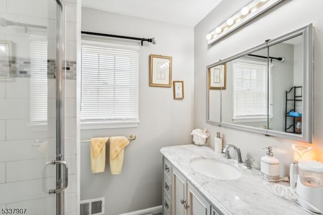 bathroom featuring vanity, a shower stall, and visible vents