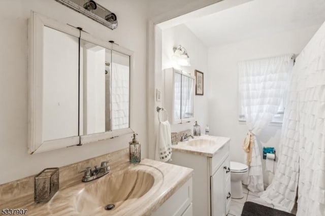 full bathroom with two vanities, a sink, and toilet