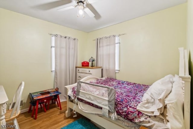 bedroom featuring ceiling fan, multiple windows, and wood finished floors