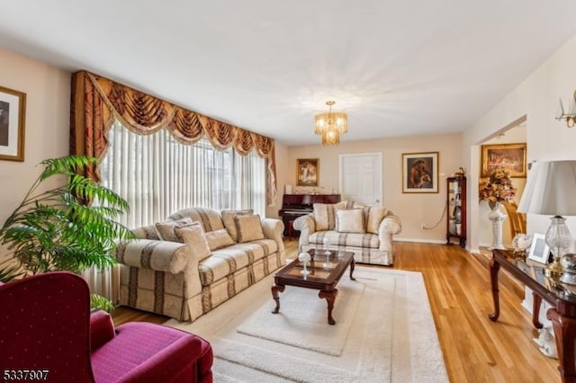 living area with a chandelier, baseboards, and wood finished floors