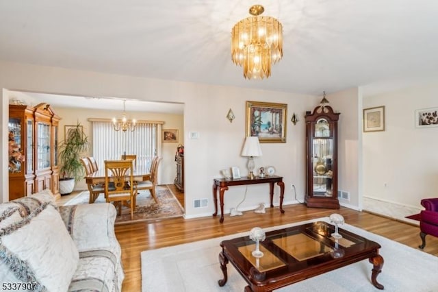 living area with an inviting chandelier, visible vents, and wood finished floors