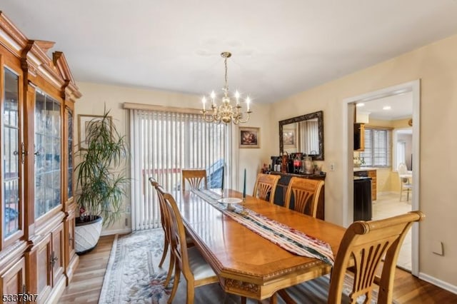 dining area with a notable chandelier, baseboards, and wood finished floors