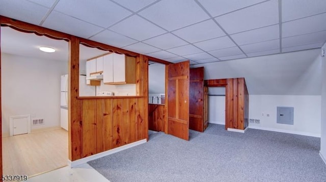 kitchen featuring white cabinetry, light carpet, a paneled ceiling, and electric panel