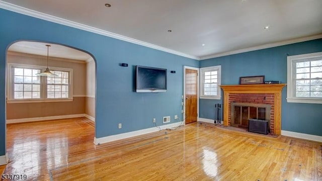 unfurnished living room featuring hardwood / wood-style flooring, ornamental molding, plenty of natural light, and a fireplace