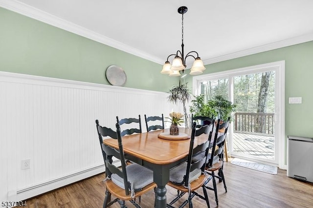 dining area with crown molding, wood-type flooring, an inviting chandelier, and baseboard heating