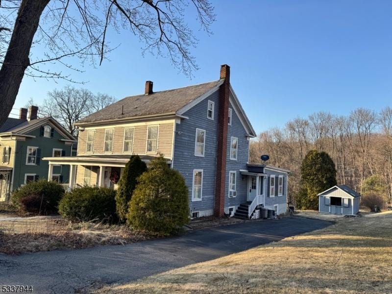 view of front facade featuring an outdoor structure, central air condition unit, and a chimney