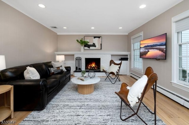 living room featuring recessed lighting, wood finished floors, visible vents, baseboard heating, and a brick fireplace