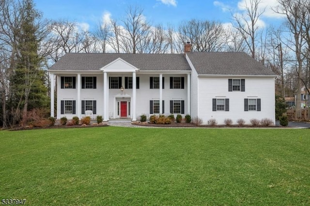 view of front of home featuring a front lawn, a chimney, and a shingled roof