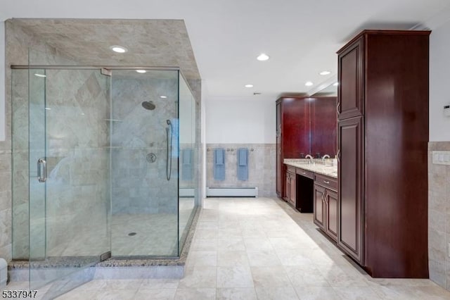 bathroom featuring tile walls, a baseboard radiator, recessed lighting, a shower stall, and vanity