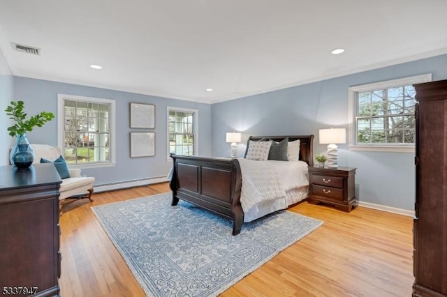 bedroom featuring multiple windows, baseboard heating, visible vents, and light wood-style floors