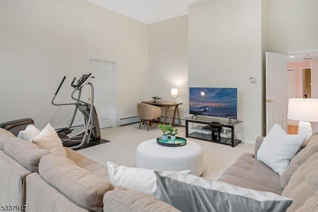 living area featuring a high ceiling, baseboard heating, carpet flooring, and baseboards