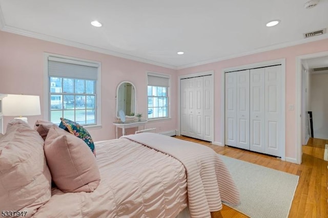 bedroom with light wood finished floors, visible vents, crown molding, two closets, and recessed lighting