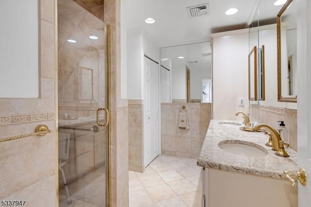 bathroom with visible vents, a sink, tile walls, and a shower stall