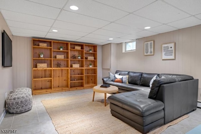 tiled living room featuring a paneled ceiling, wooden walls, and recessed lighting