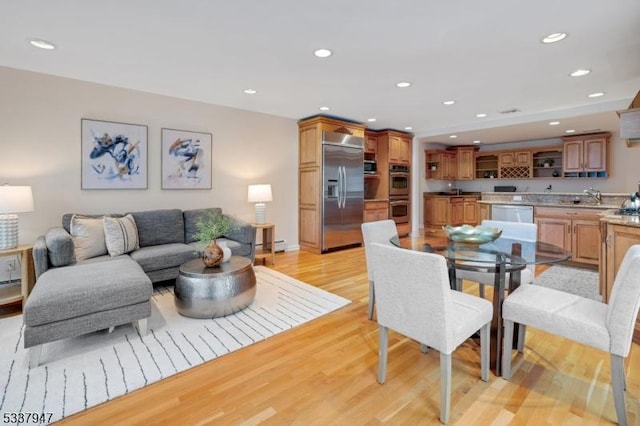 living area with light wood-style floors, recessed lighting, and baseboard heating