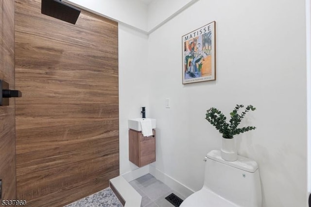 full bathroom with tiled shower, vanity, toilet, and baseboards