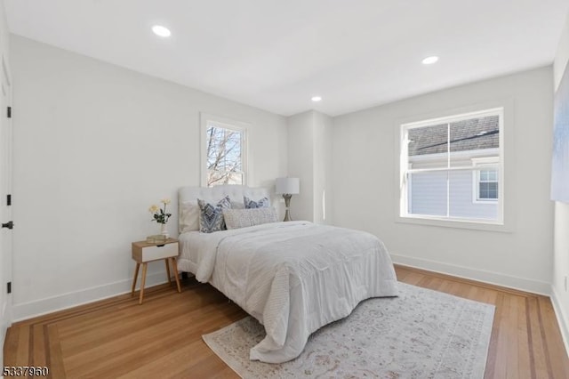 bedroom with baseboards, wood finished floors, and recessed lighting