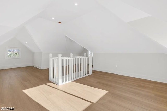 bonus room with light wood-style flooring, baseboards, and vaulted ceiling