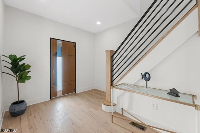 foyer entrance with stairway, wood finished floors, visible vents, and baseboards