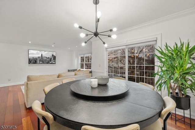 dining space featuring ornamental molding, a notable chandelier, baseboards, and wood finished floors