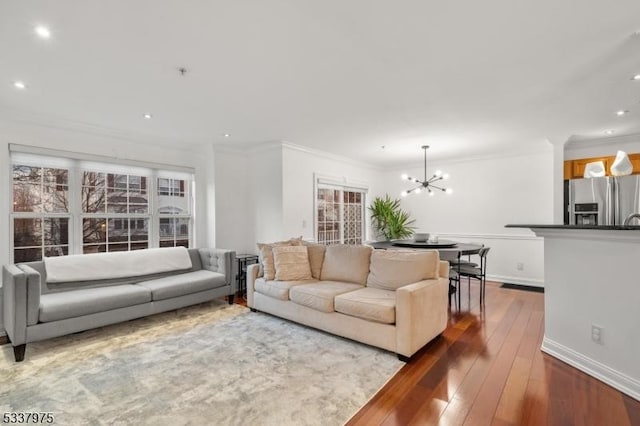 living area featuring dark wood-type flooring, ornamental molding, baseboards, and an inviting chandelier