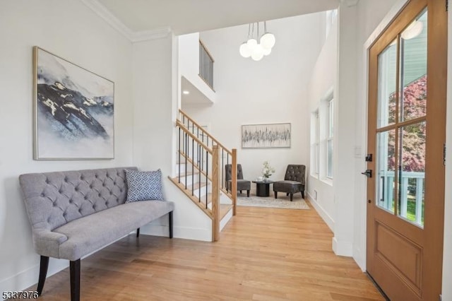 entryway featuring an inviting chandelier, crown molding, a wealth of natural light, and light hardwood / wood-style floors