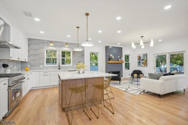 kitchen featuring stainless steel stove, white cabinetry, a kitchen breakfast bar, ornamental molding, and a kitchen island