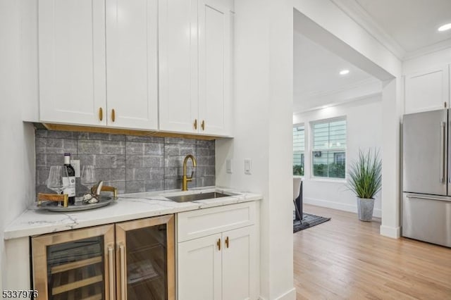 bar featuring white cabinetry, sink, high end refrigerator, wine cooler, and ornamental molding