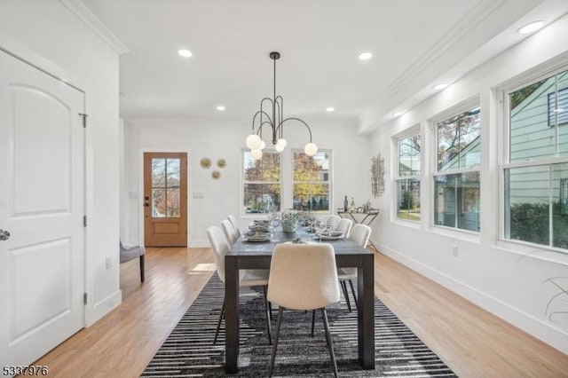 dining space featuring ornamental molding, a notable chandelier, and light hardwood / wood-style floors