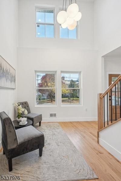 sitting room featuring hardwood / wood-style floors, a towering ceiling, and a notable chandelier